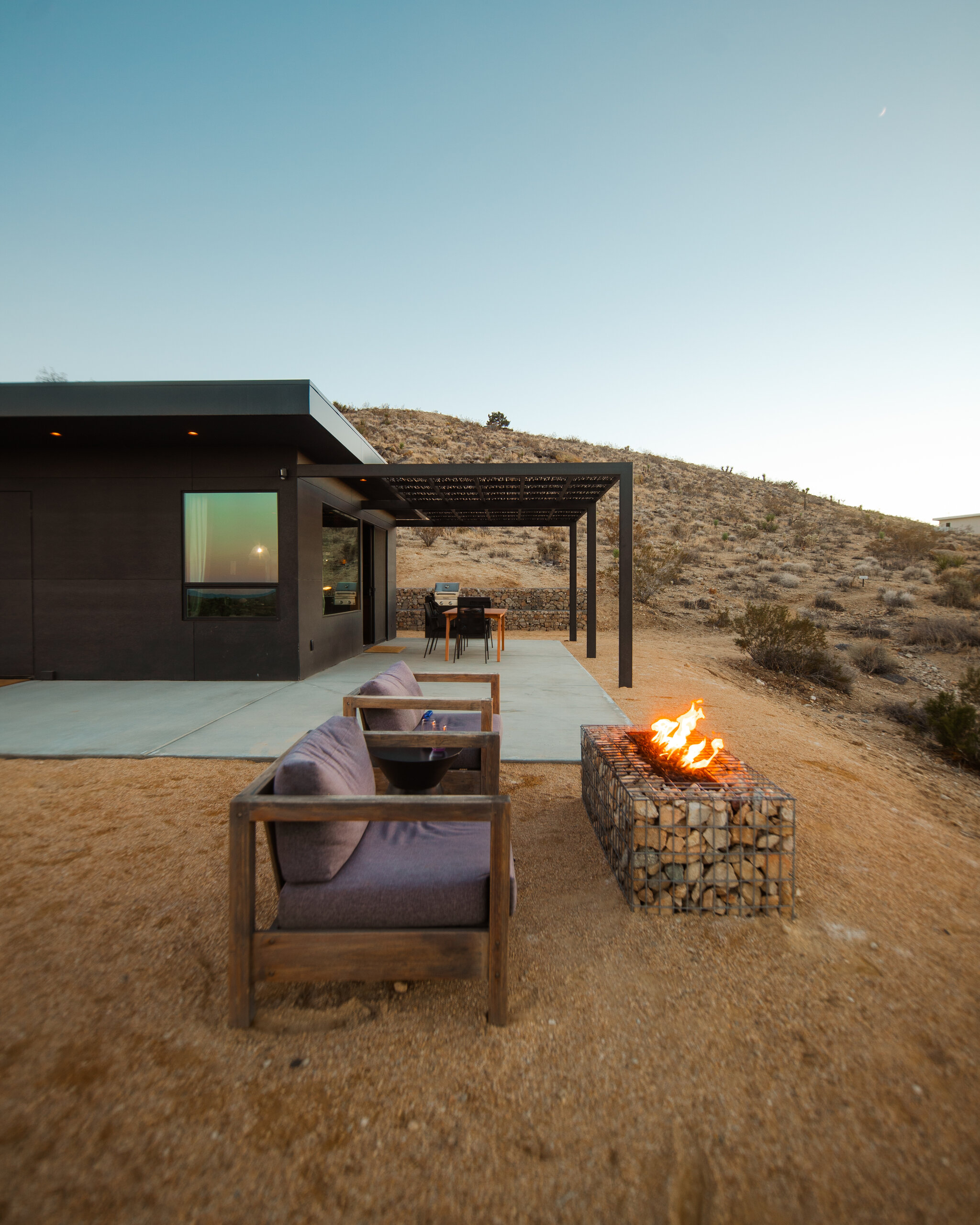 Couple by the fire pit in a golden desert field near Pause House