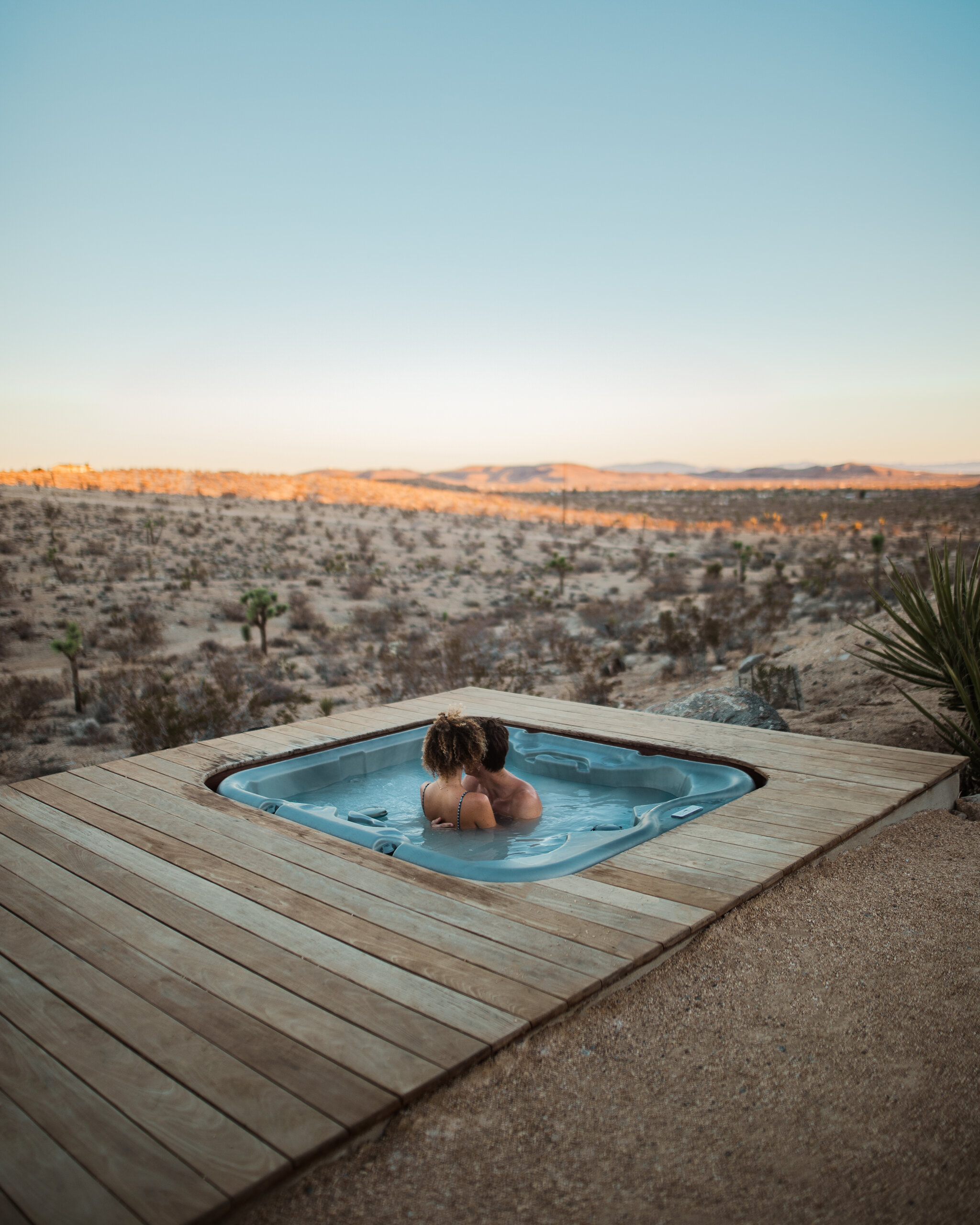 Couple in the hot tub at Pause House AM at dusk with the desert valley beyond